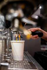 Close-up of a barista’s hand operating an espresso machine, filling a white cup with fresh coffee, capturing the artistry of coffee making