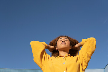 Young woman with eyes closed under clear blue sky on sunny day
