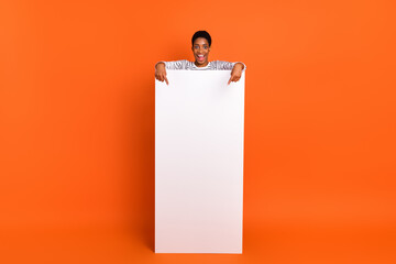 Full length body size view of attractive cheerful girl demonstrating copy space ad tips offer isolated over vibrant orange color background