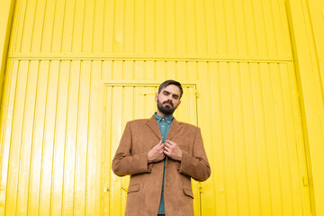 Man wearing brown jacket and standing in front of yellow building