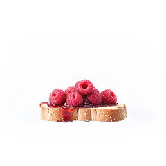 Raspberry jam dollop rich and seeded plopping onto a piece of toast with whole raspberries