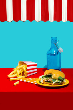 Chicken burger with french fries near soda bottle on table against blue background