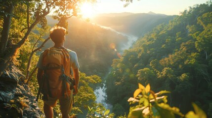 A Caucasian man standing on the edge of a cliff, overlooking a lush forest at sunset