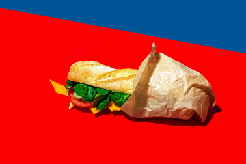Cheese sandwich wrapped in paper on red background