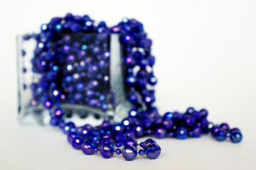 Transparent square vase with blue beads on a white background	
