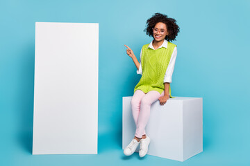 Full size photo of charming cute girl sitting cube podium advertise cellphone product isolated on...