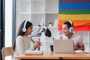 A young gay man and his girlfriend use a laptop and microphone to stream podcast audio at a studio talking about gender liberation.
