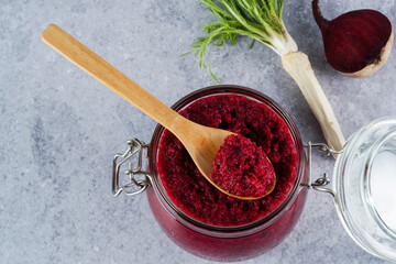 Creamy beet horseradish sauce in jar with a wooden spoon on top on a gray background. Appetizer or condiment for meat and fish. Healthy vegan food. top view.