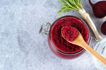 Creamy beet horseradish sauce in jar with a wooden spoon on top on a gray background. Appetizer or...