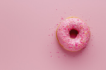 An appealing image of a donut with pink icing and a burst of colorful sprinkles, symbolizing indulgence and fun against a pink backdrop - Powered by Adobe
