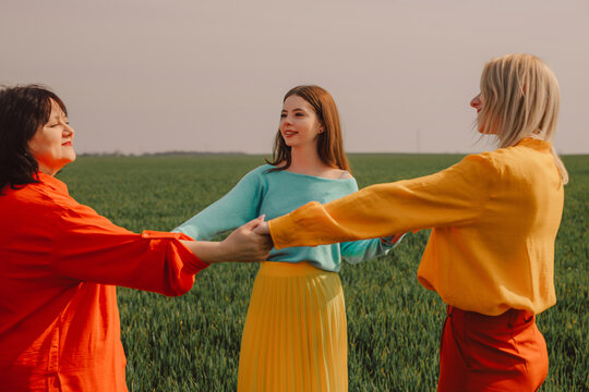 Happy family holding hands and standing on green wheat field
