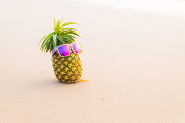 Funny pineapples in stylish sunglasses on the sand..