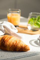 Fresh croissant for breakfast on white board. Delicious celebratory breakfast in sunlight. Bakery or confectionery. Romantic morning meal.