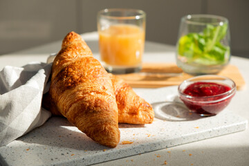 Fresh croissant for breakfast with jam on white board. Delicious celebratory breakfast in sunlight....