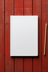 Blank white book with a pencil on a red wooden background