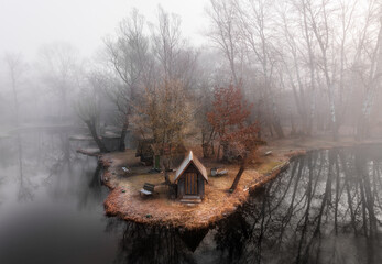 Szodliget, Hungary - Aerial view of a dreamy winter scene at Szodliget fishing lake with fishing huts and heavy fog on a cold winter morning