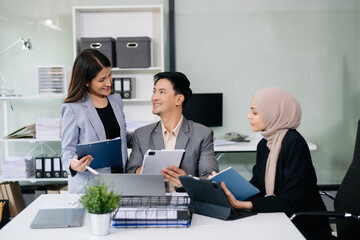 Group of young Asian business people discussing business plan at modern startup in creative business discussing work