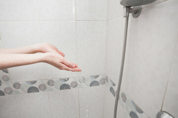 Washing hands under the shower in a bright bathroom. The girl washes and takes care of her body....