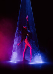 Ballet dancer in pointe under multicolor neon laser light on stage. Woman ballerina posing in dark room. Performance, projection mapping. Interactive installation, Optical visuals concept