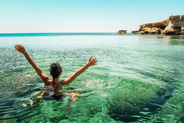 Woman enjoy vacation swim in Northern cyprus. Ayia napa bay shore with crystal clear blue...