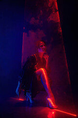 Stylish woman in latex coat under colorful illumination, laser light, neon smoke club. Projection...