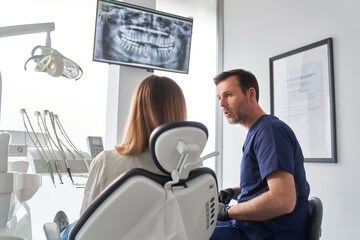 Dentist discussing panoramic digital X-Ray of a patient's teeth