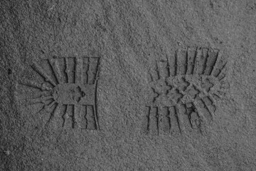 The footprints of a boot are traces of a person on moist soil that begins to dry out from the sun, shoe prints on soft ground, photo during the day