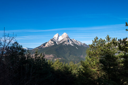 Verdant forests frame the rugged Pedraforca peak in Catalonia, Spain, showcasing the mountain's natural splendor and greenery