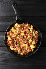 Corned beef hash with potatoes in iron cast pan