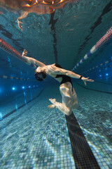 girl doing synchronized swimming in the pool advertising underwater photography