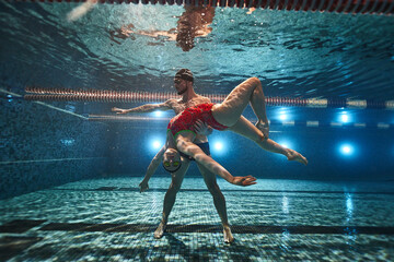 young athletes swimmers dive in the pool and under the water the guy holds the girl in his arms....