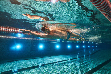 an athletic man swims in the pool. swimmer. underwater photography. freestyle swimming - obrazy, fototapety, plakaty