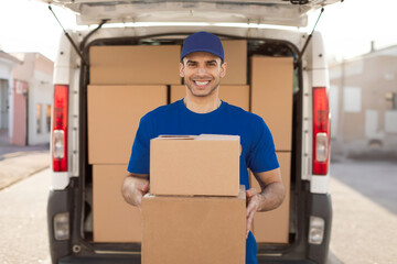 Young european male postal delivery courier man holding delivering package boxes and smiling....
