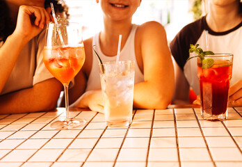 Close-up of three charming girls drinking chilled cocktails in a cafe. Glasses with delicious fruit...