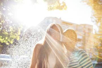 Two cute teenage girls are standing by the fountain and smiling. Highlight.