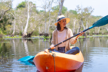 Happy asian couple rowing a canoe or kayak in mangrove forests. Beautiful botanical garden,...