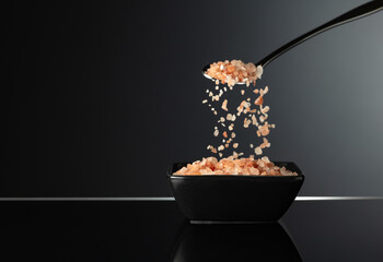 Pink Himalayan salt in a small black ceramic bowl.