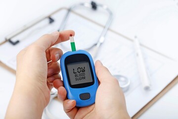 Hand holding blood glucose meter measuring blood sugar background is stethoscope chart file 20