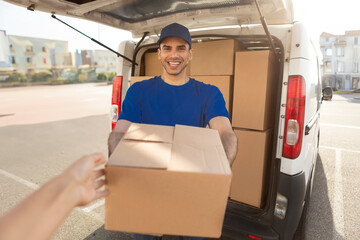 Man in uniform delivering parcel to female customer, giving cardboard box to woman. High quality...