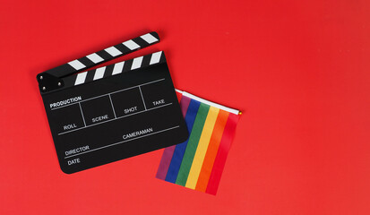 Fototapeta na wymiar Clapper board and rainbow pride flag on red background.