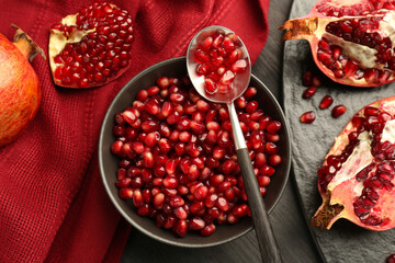 Tasty ripe pomegranates and grains on dark wooden table, flat lay