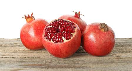 Fresh pomegranates on wooden table against white background