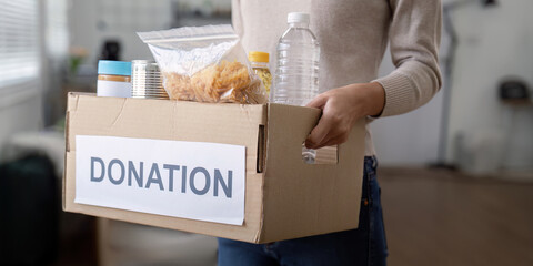 Woman volunteer holding food donation box at home