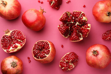 Whole and cut fresh pomegranates on pink background, flat lay