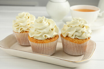 Tasty cupcakes with vanilla cream on white wooden table, closeup