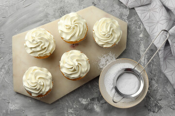 Tasty cupcakes with vanilla cream on grey table, top view