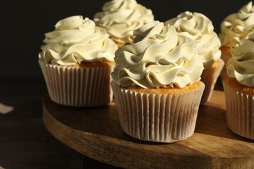 Tasty cupcakes with vanilla cream on wooden stand, closeup