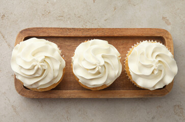Tasty cupcakes with vanilla cream on light grey table, top view