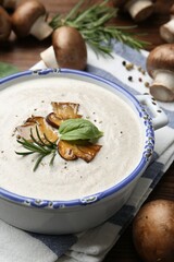 Delicious homemade mushroom soup in ceramic pot and fresh ingredients on wooden table