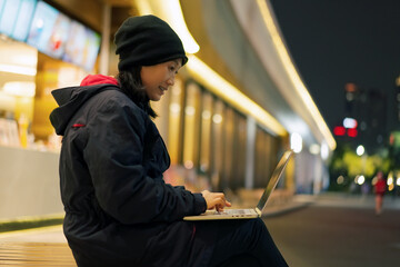 Young Woman Working on Laptop Outdoors at Night